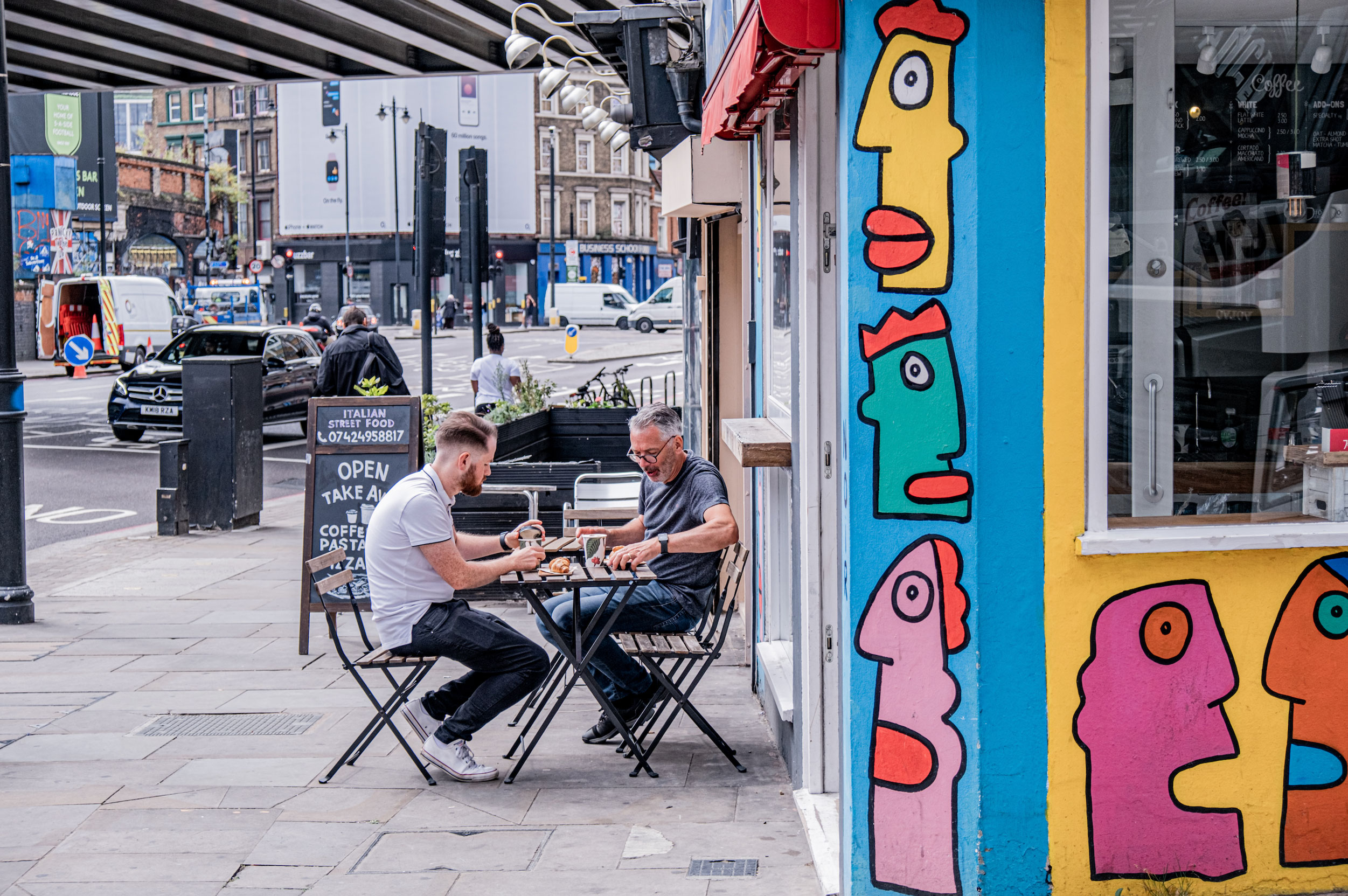 Street photo of two men having lunch on terrace in London.